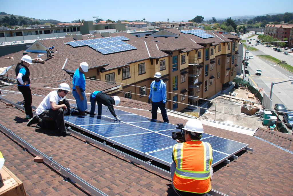 A group of workers installs solar on a multifamily affordable housing unit. 